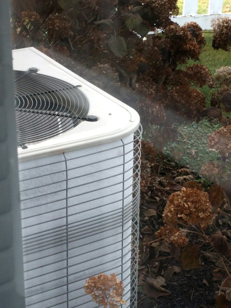 Malfunctioning HVAC outdoor heat pump unit completely frozen, covered in ice, broken won't defrost